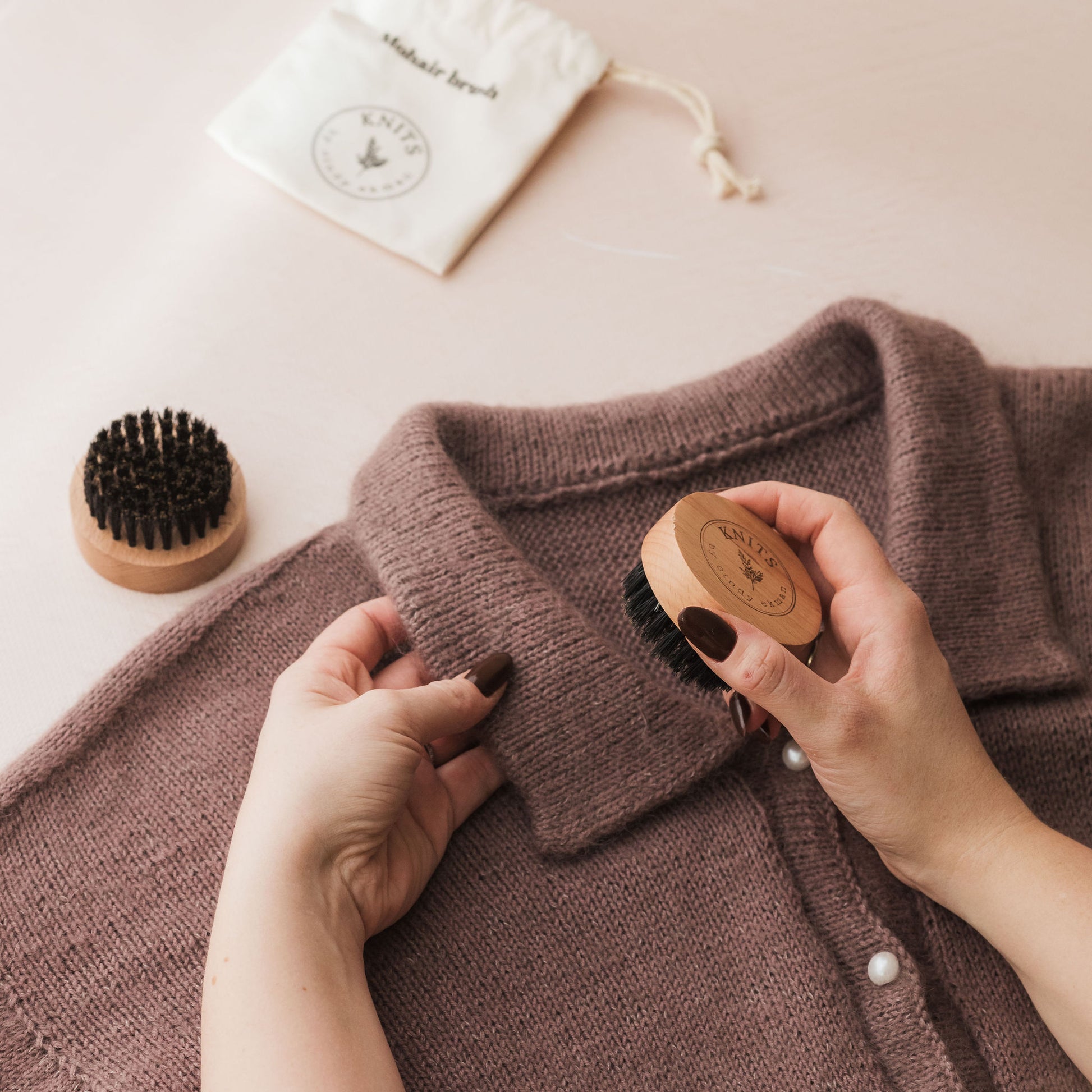 Person using a wooden brush on a brown garment with a white background