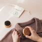 Person using a wooden garment brush on a brown sweater with a white drawstring bag in the background.