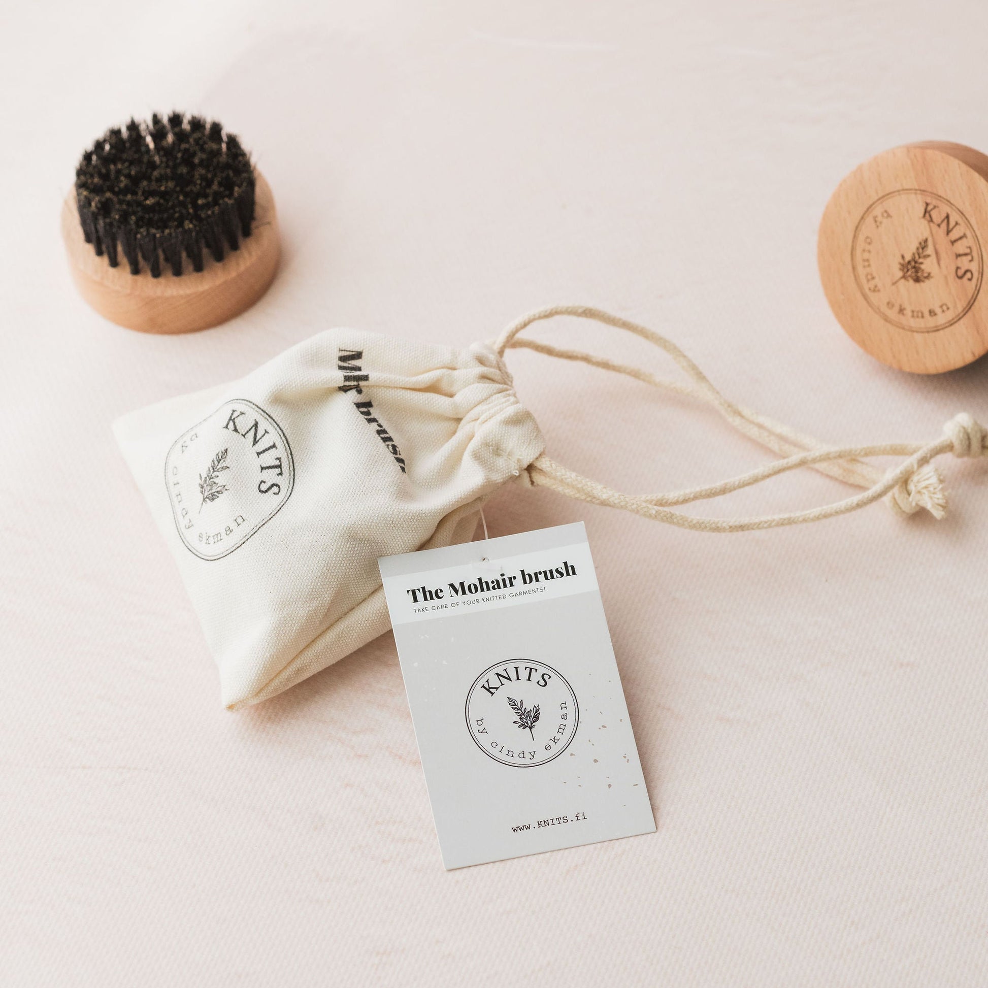 Set of natural knitted garment care products including a brush, and packaging on a light background