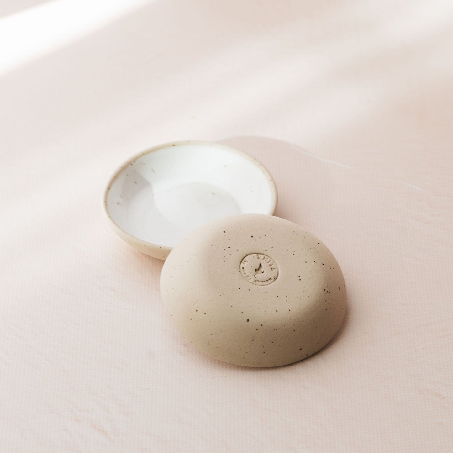 Two beige ceramic bowls on a light pink background