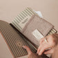 Person holding a striped notebook with a textured cover
