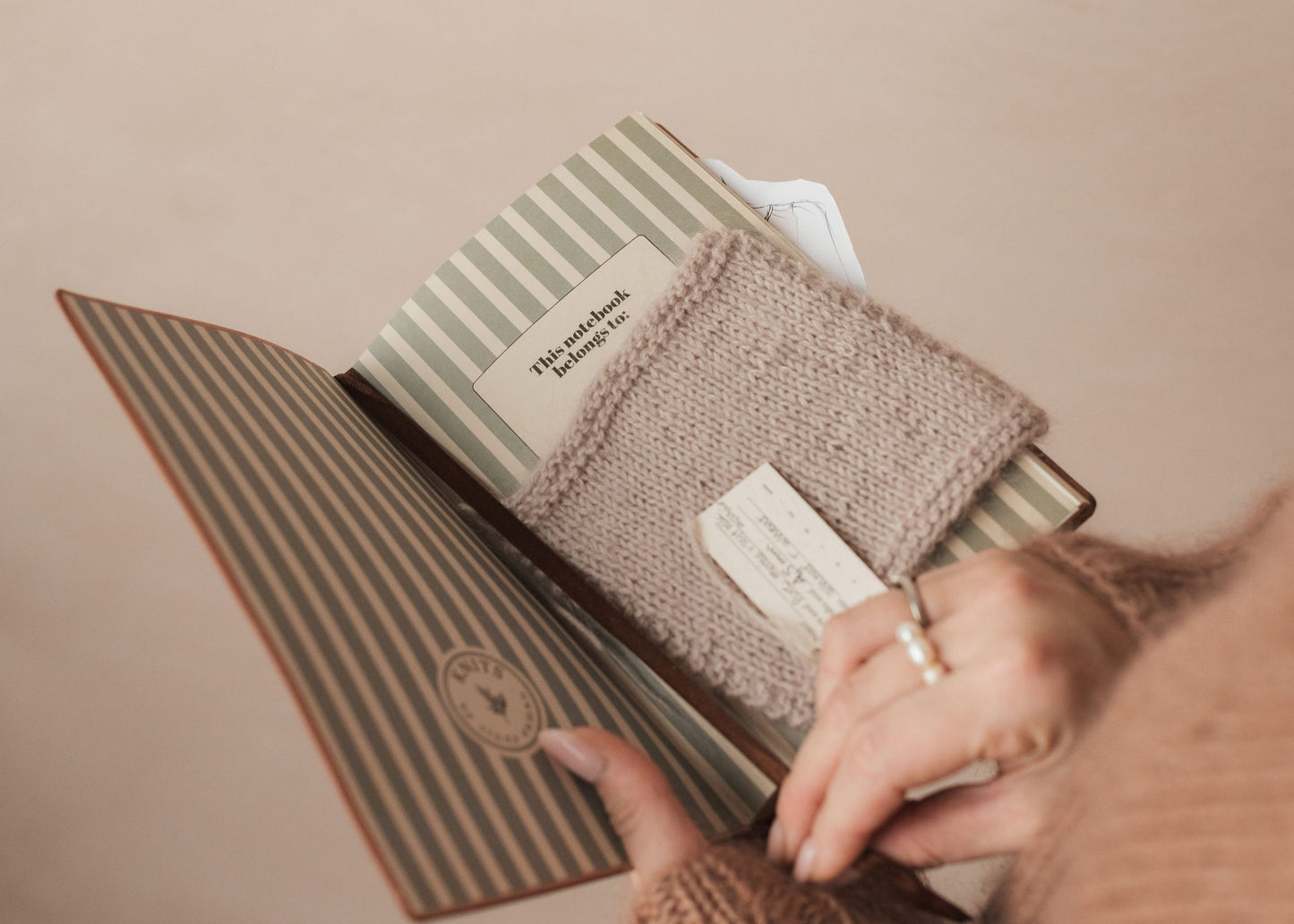 Person holding a striped notebook with a textured cover