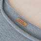 Gray knitted blanket with a label reading 'Made for a loved one' on a beige background