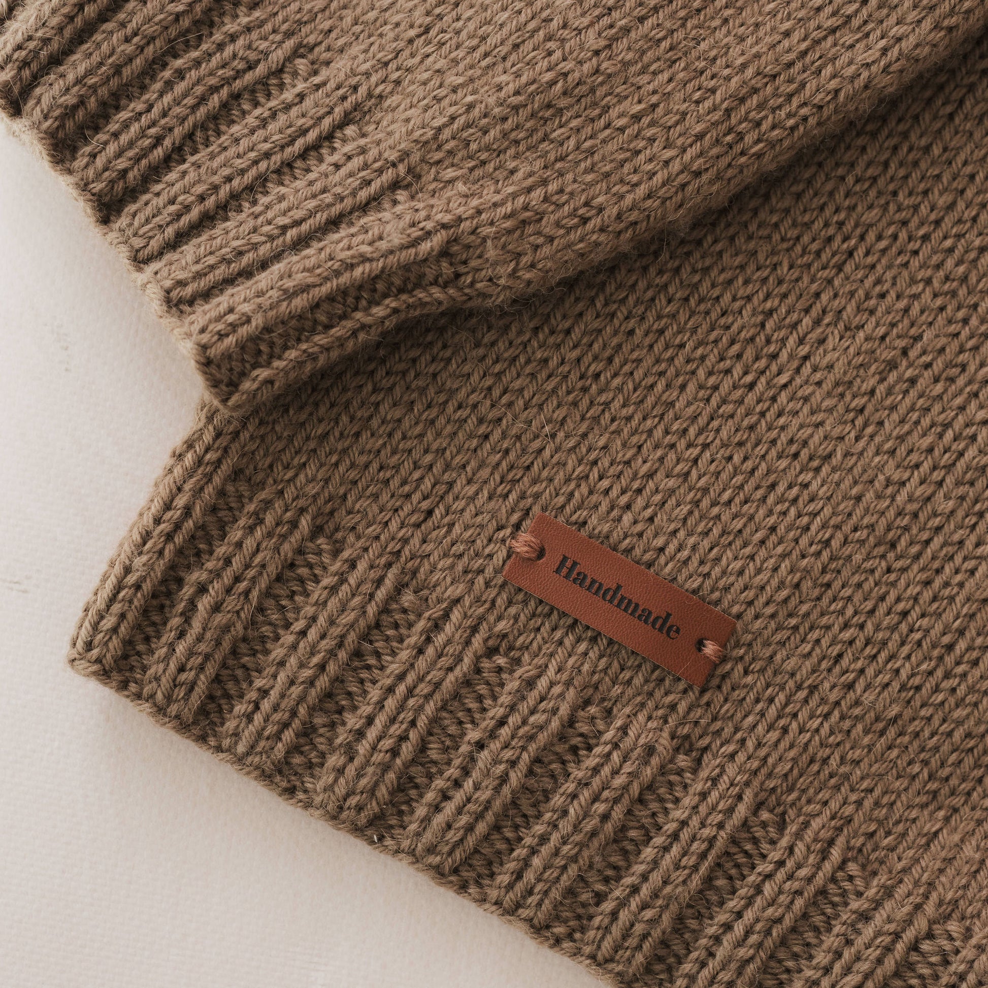 Olive green knitted fabric with a 'Handmade' label on a light background