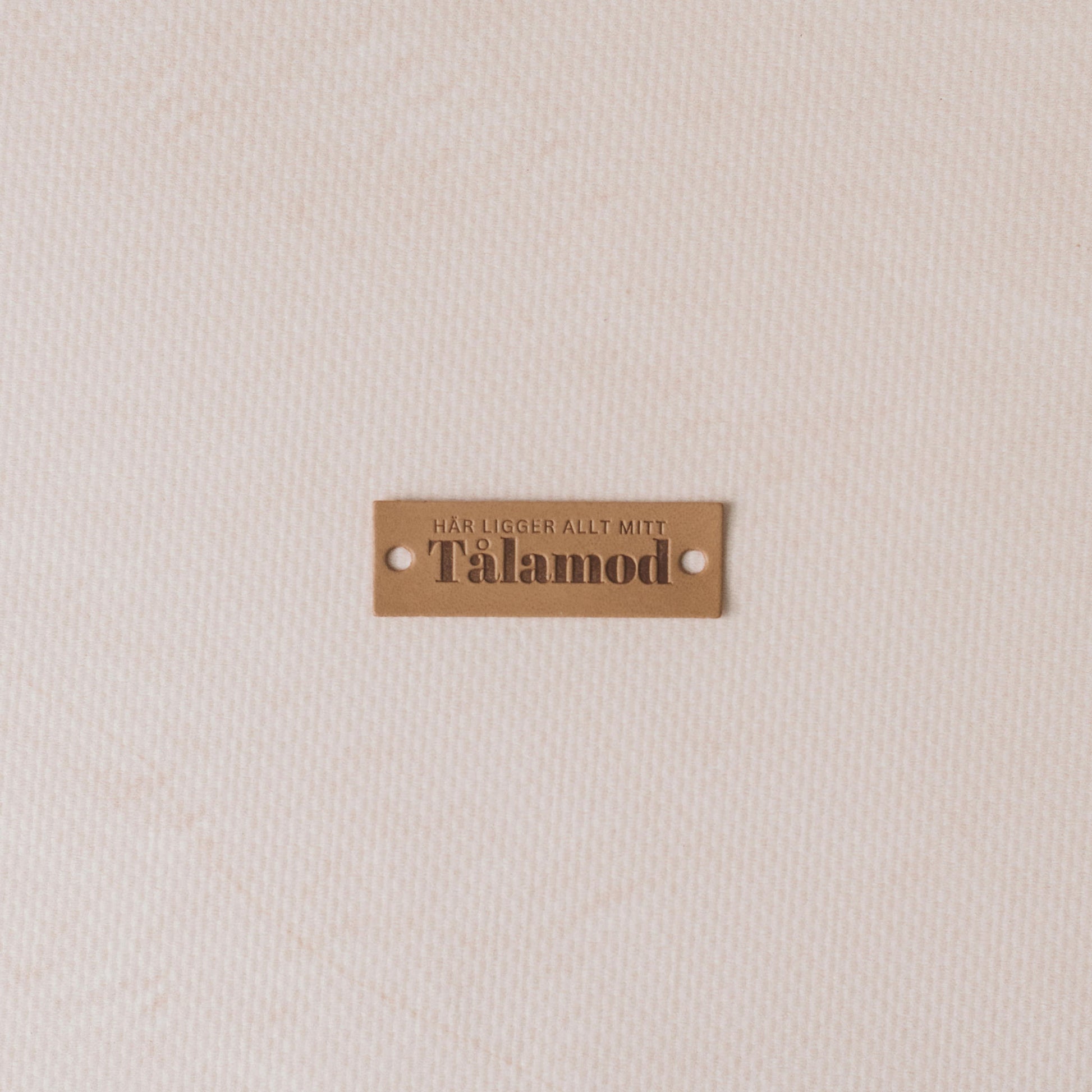 Tålamod label on a textured beige background