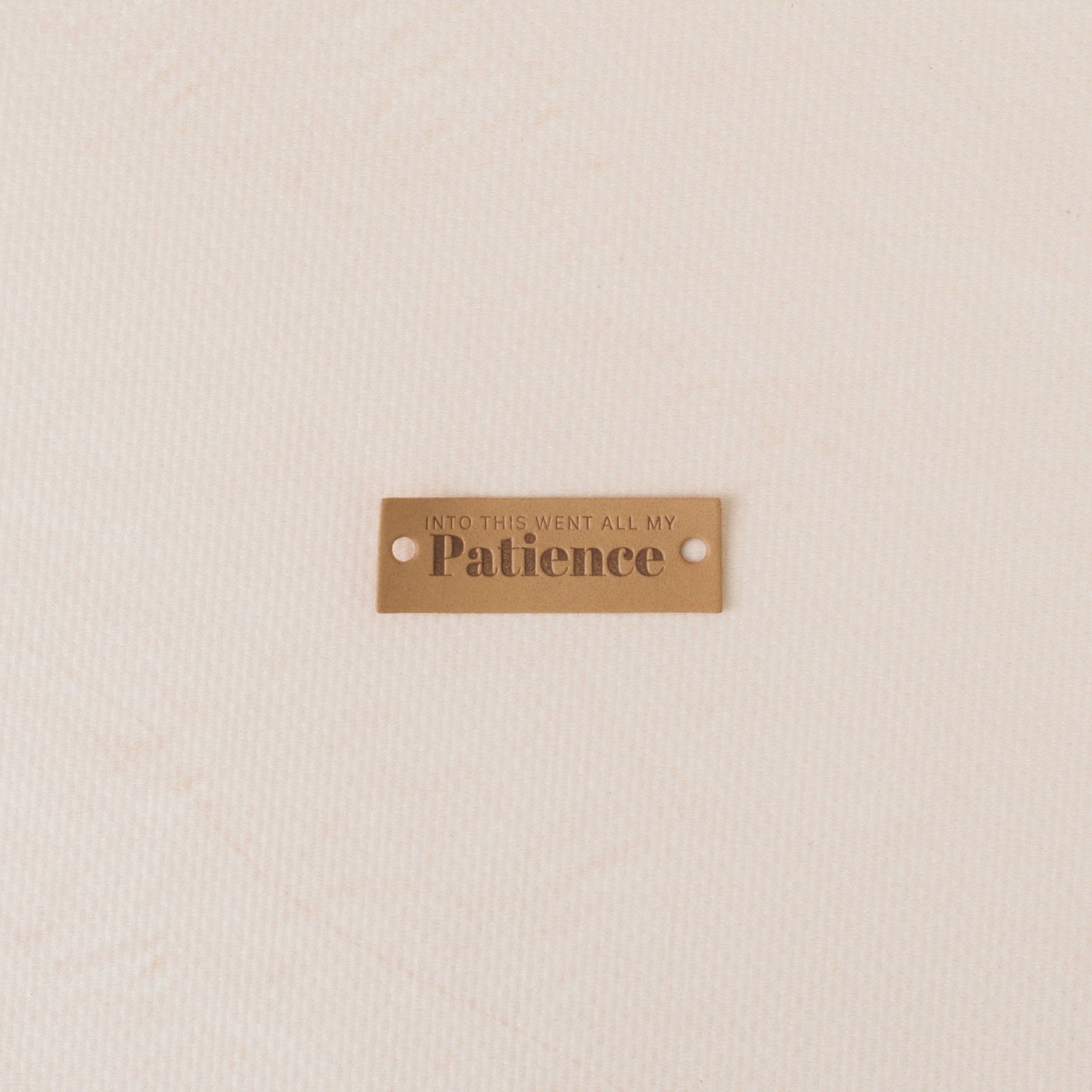 PUI leather tag with engraved text on a beige background, into this went all my patience