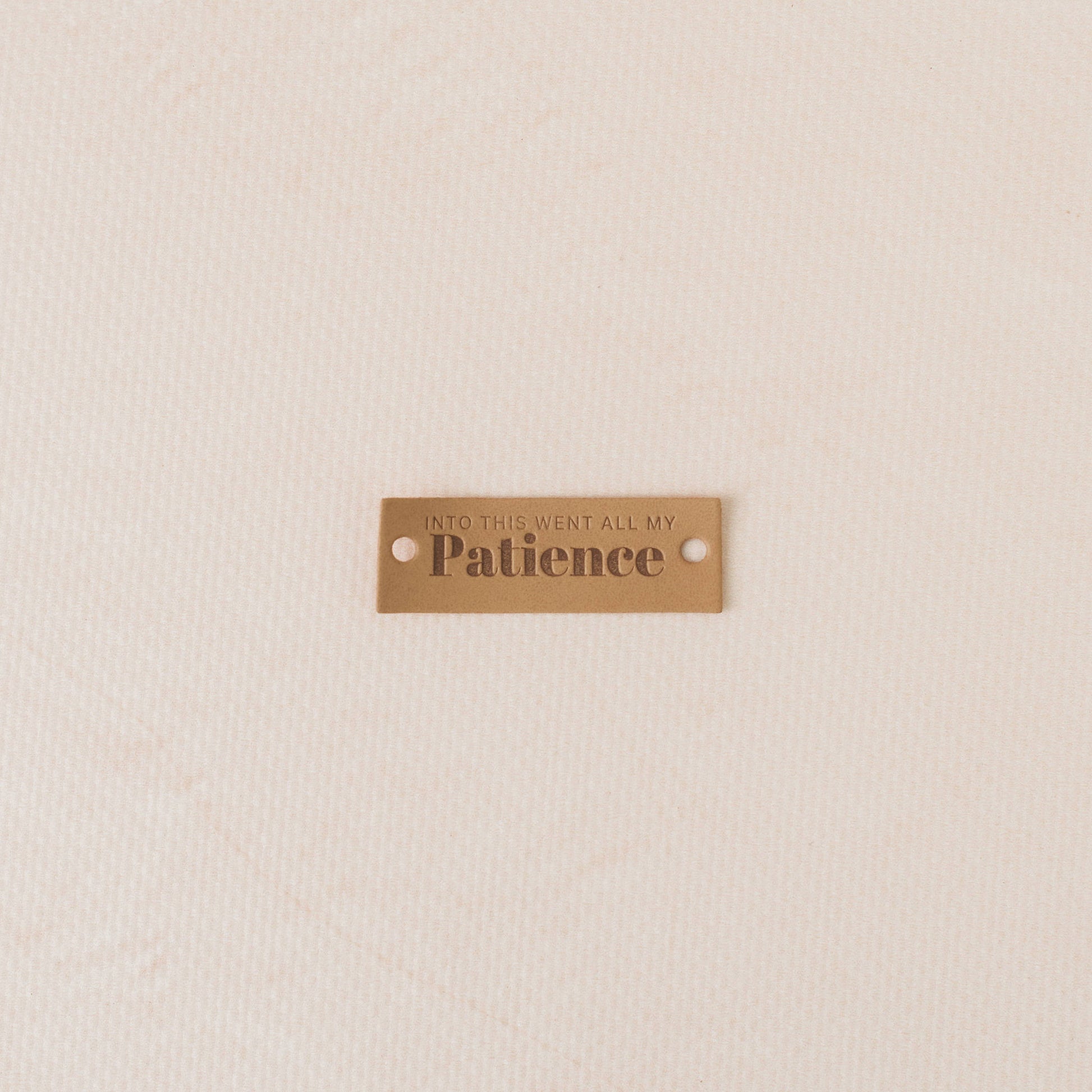 PUI leather tag with engraved text on a beige background, into this went all my patience