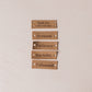 Set of five brown leather labels with engraved text on a beige background