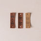 Three brown leather tags with text on a beige background