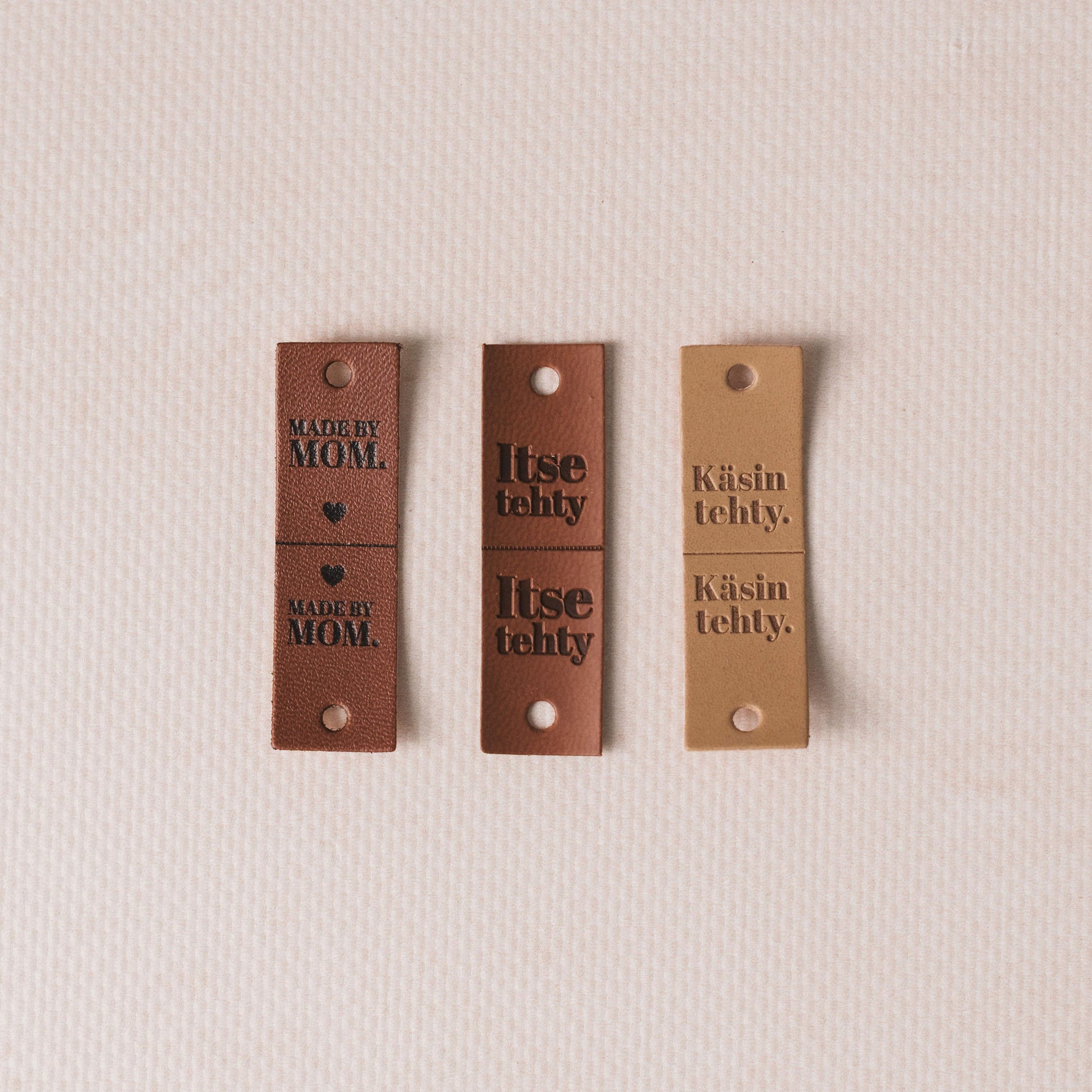 Three brown leather tags with text on a beige background