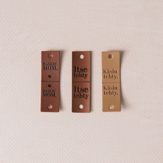 Three brown leather tags with text on a beige background