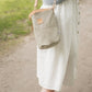 Person wearing a light green bag, white skirt, and brown shoes on a path.
