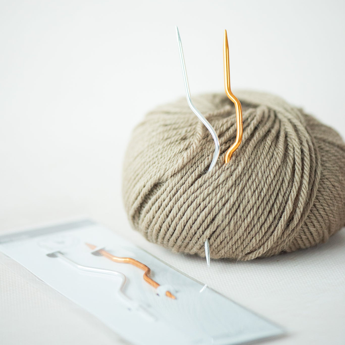 Ball of yarn with a knitting needle on a light surface